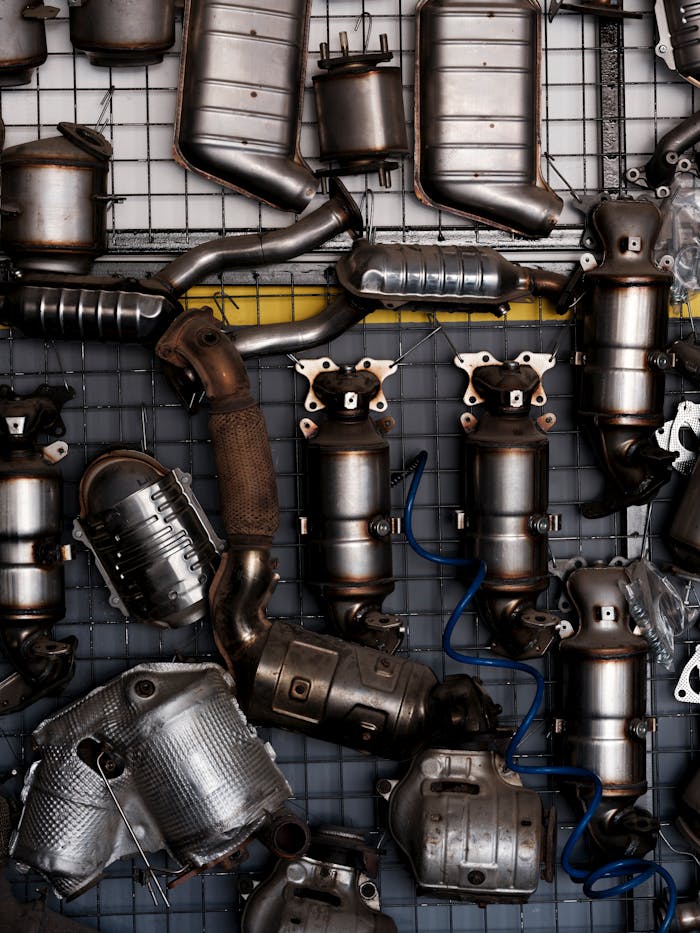 Collection of vintage car exhaust parts hanging in an industrial workshop setting.